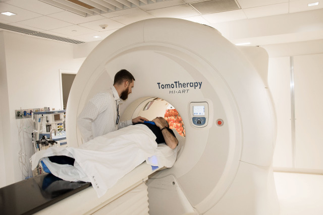 Radiation therapy technician Andrew Brown talks with a patient prior to treatment for prostate cancer. (PHOTO BY RICHARD WHELSKY)