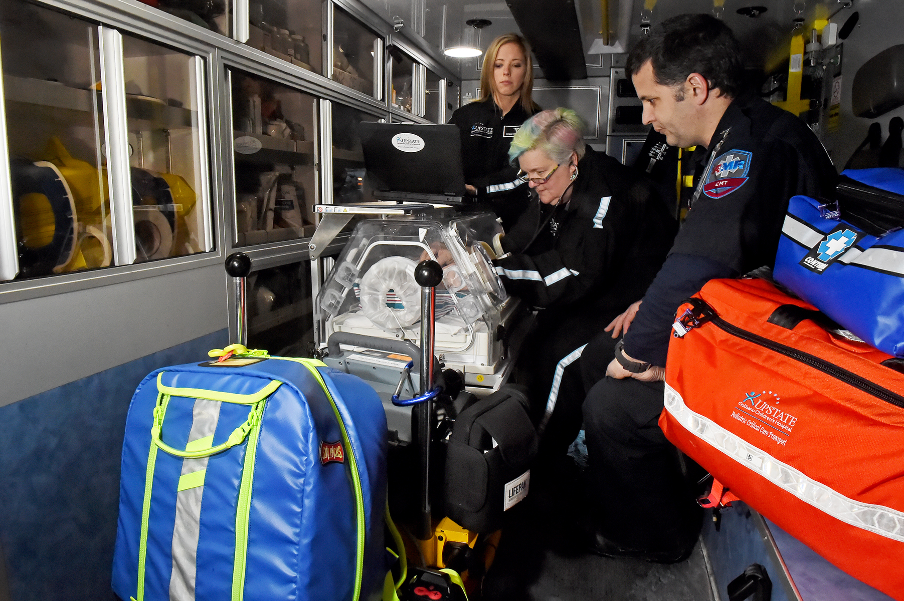 Nurses Arlinda Carey and Melanie Charleston prep an incubator in the back of an ambulance at Upstate University Hospital‘s downtown emergency department. They are members of Upstate‘s pediatric critical care transport team who offer intensive care to critically ill children at other hospitals from the Canadian to the Pennsylvania borders. They are pictured with emergency medical technician Marc Battaglia, right. (PHOTO BY JOHN BERRY)