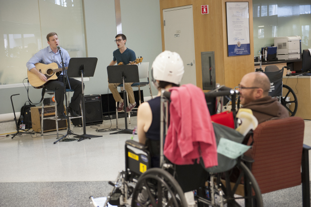 Medical students Benjamin Meath and Joe DeRaddo perform in the Upstate University Hospital lobby as Abigail and Stephen McSweeney listen. (PHOTO BY SUSAN KAHN)
