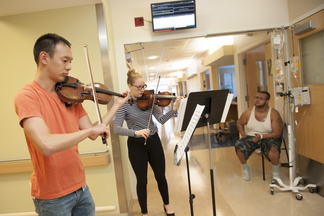 Medical student Joshua Rim and Dona Occhipinti of Welch Allyn perform for Aaron Johnson, a patient. (PHOTO BY SUSAN KAHN)