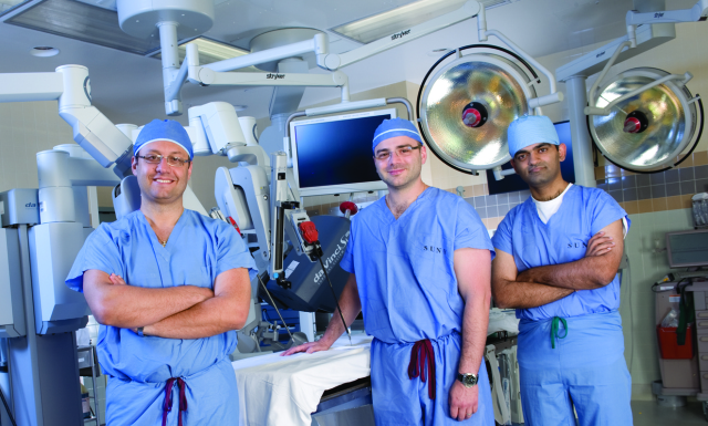 From left, urologists Gennady Bratslavsky, MD, Oleg Shapiro, MD, and Rakesh Khanna, MD, in one of the robotic surgery suites. Upstate has 13 robotically trained urologic surgeons, performing the highest volumes in the region. Other distinctions include the region‘s first thoracic and hepatobiliary robotic surgery teams, to treat cancer and other conditions involving the chest, liver, gallbladder and pancreas. (photo by Susan Kahn)