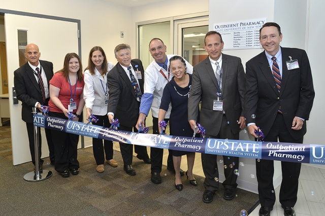 Cutting the ribbon to open the Upstate outpatient pharmacy are, from left, Upstate University Hospital Interim CEO Robert Corona, DO, Pharmacy Technician Stephanie McDevitt, Pharmacist Emily Adamy, Pharmacy Director Luke Probst, Pharmacist David Geloso, Upstate Medical University President and Health System CEO Danielle Laraque-Arena, MD, Associate Director of Pharmacy Enterprise Eric Balotin, and Upstate Chief Financial Officer Stuart Wright. (Photo by Debbie Rexine)