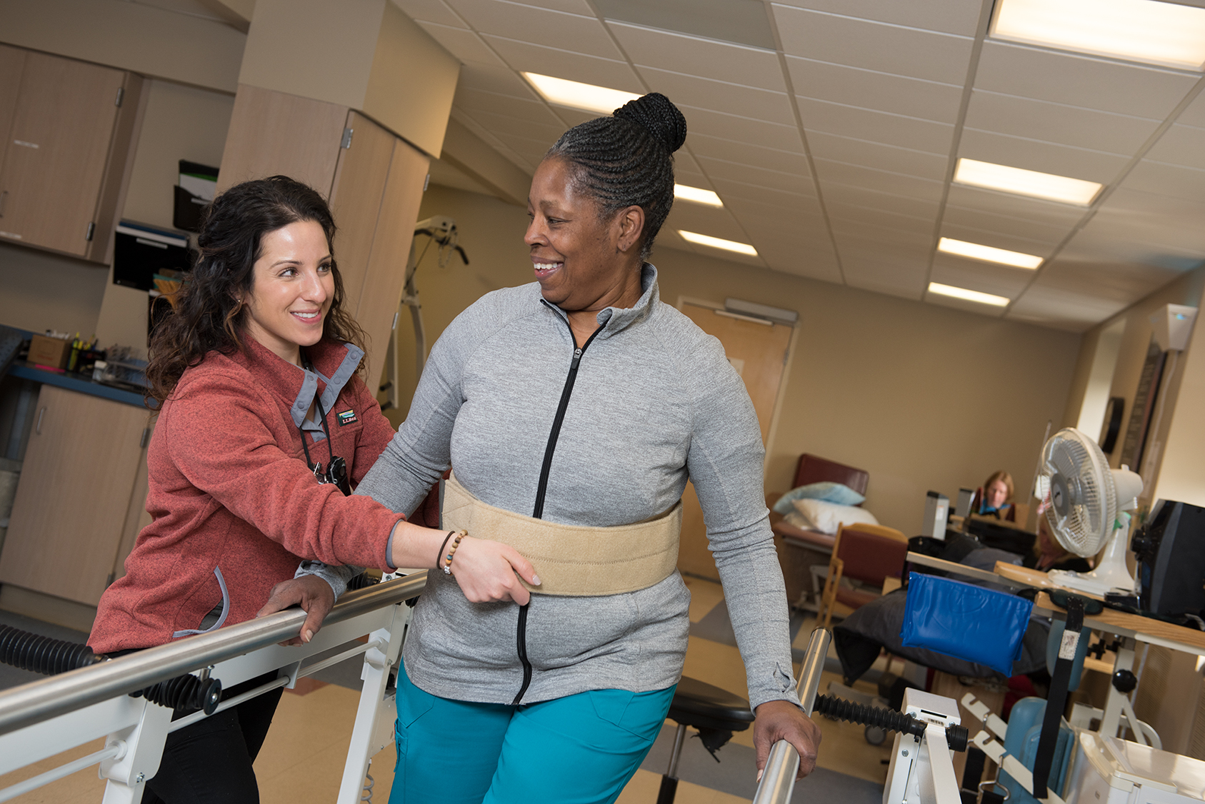 Physical therapist Nicole Conese, left, and Karen Renfroe demonstrate walking with a back support in the rehabilitation center at Upstate University Hospital's Community campus. (photo by Susan Kahn)