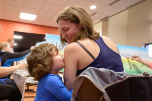 Alayah Green, 4, kisses her mom, Katie Green, while she and other mothers of cancer patients paint landscapes at the H.O.P.E. art session led by Ally Walker.