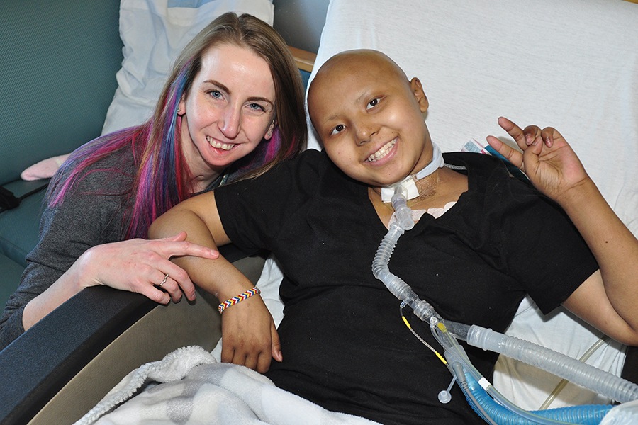 Respiratory therapist Amy Bradt talks with Muyan Pen, 14, who breathes with a ventilator because of complications from a brain tumor. (photo by Richard Whelsky)