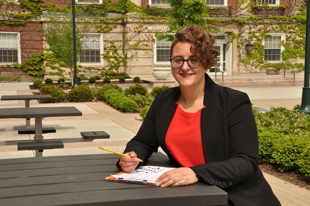 Rachel Fabi working on a crossword puzzle in the courtyard in front of Upstate’s Weiskotten Hall. (photo by Richard Whelsky)