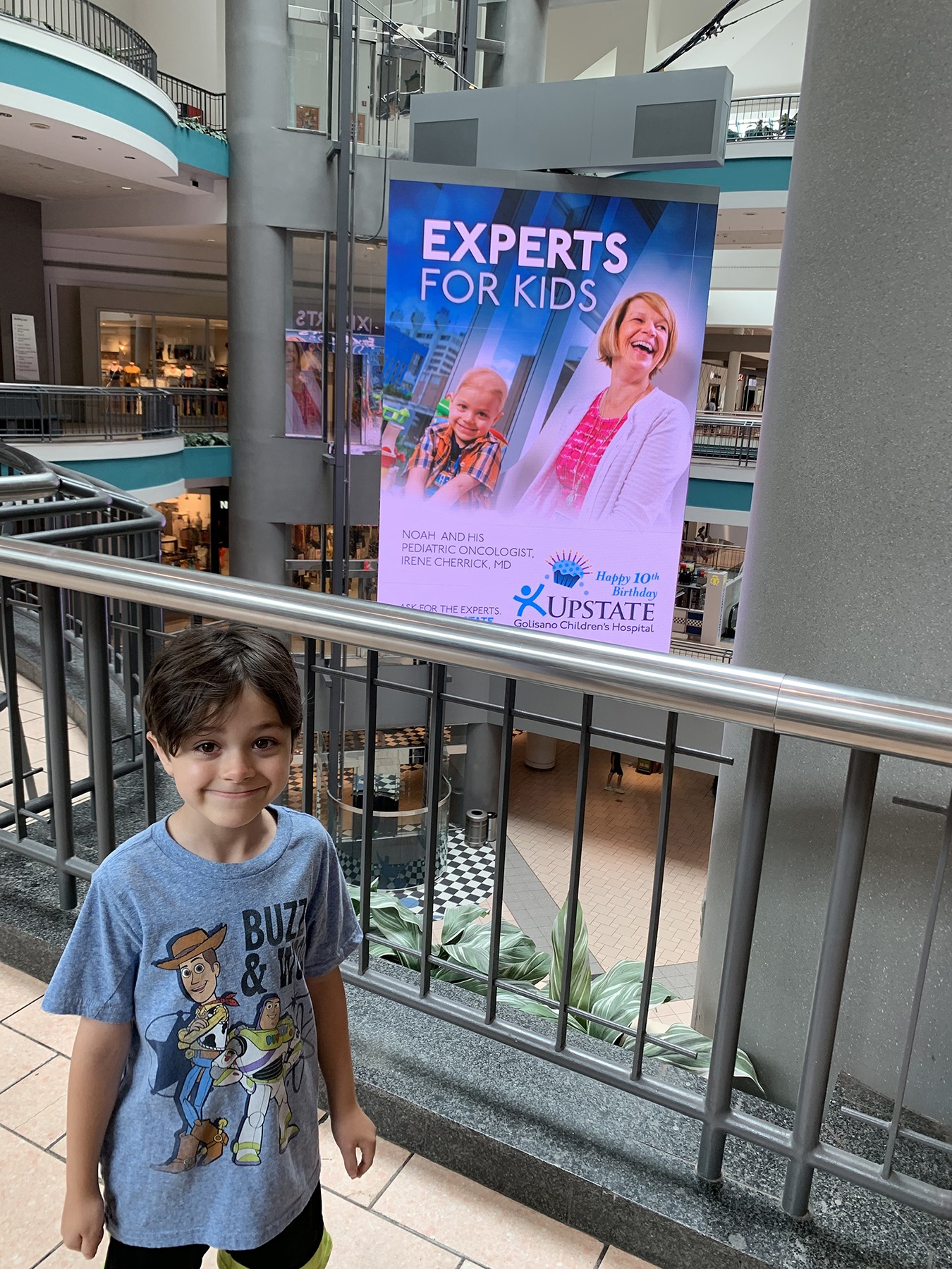 Noah Axtell, standing by a poster showing him with Upstate pediatric cancer specialist Irene Cherrick, MD. (provided photo)