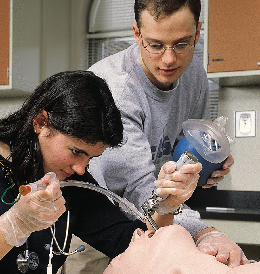 Students in a clinical skills lab at Upstate practice inserting a breathing tube into a mannequin.