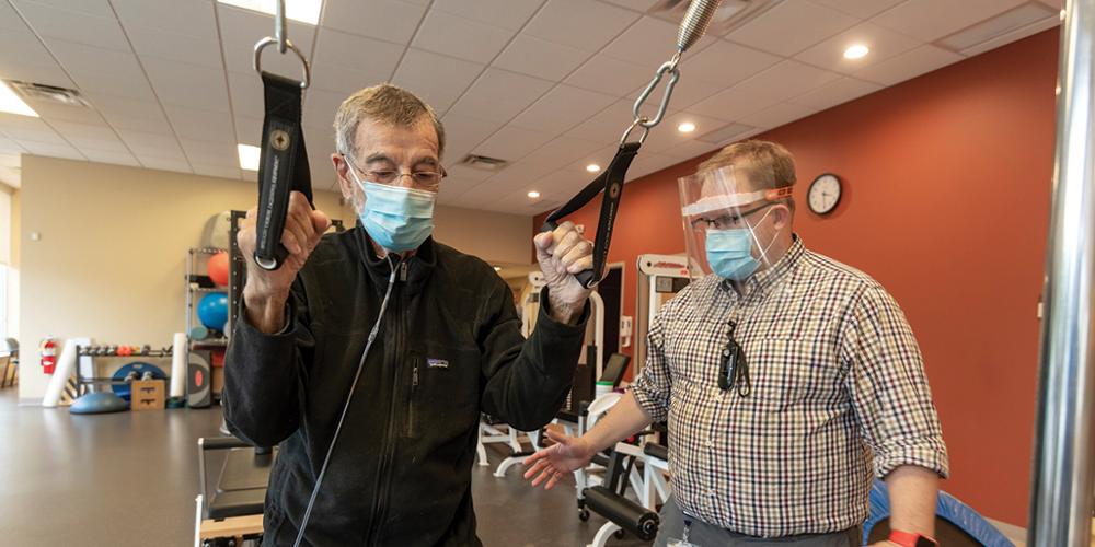 Post-COVID patient John DiGesare, left, exercises under the guidance of physical therapist Matt Bowman at Upstate Rehabilitation at Western Lights, one of several Syracuse-area locations offering such therapy.