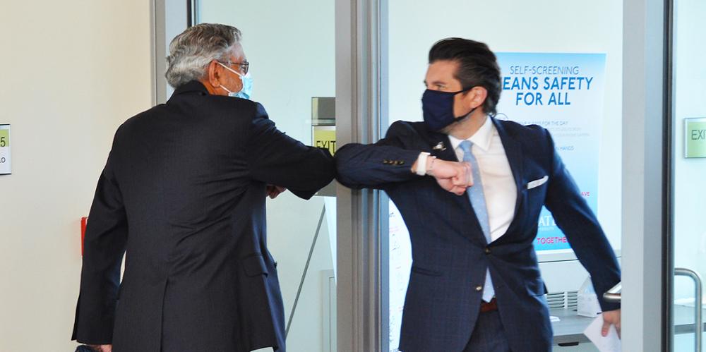 Upstate President Mantosh Dewan, MD, left, greets SUNY Chancellor Jim Malatras, PhD, who visited Upstate to see its COVID testing procedures.