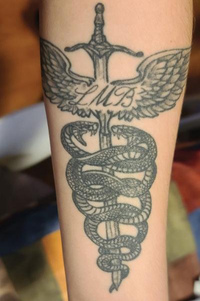 Jacquelyn Cox’s tattoo combines a late friend’s initials with a nod to Greek mythology and nursing through an original caduceus design.