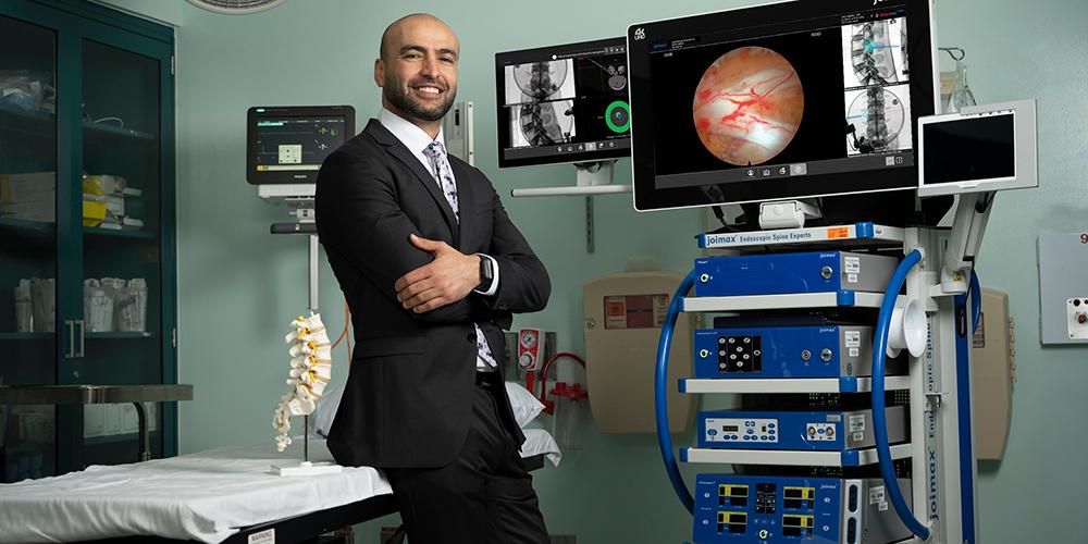 Neurosurgeon Ali Hazama, MD, with a screen showing the image provided by the endoscopic device. Hazama specializes in endoscopic spinal surgeries, which minimize cutting, scarring, pain and time of recovery. 