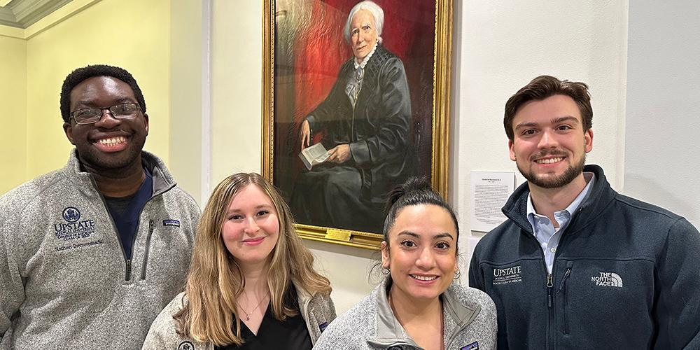 Presidents of the classes of the Norton College of Medicine gather by the portrait of Blackwell. From left: Nathan Ihemeremadu, Gavrielle J. Rood, Katherine Narvaez Mena and Christopher Bushnell. 